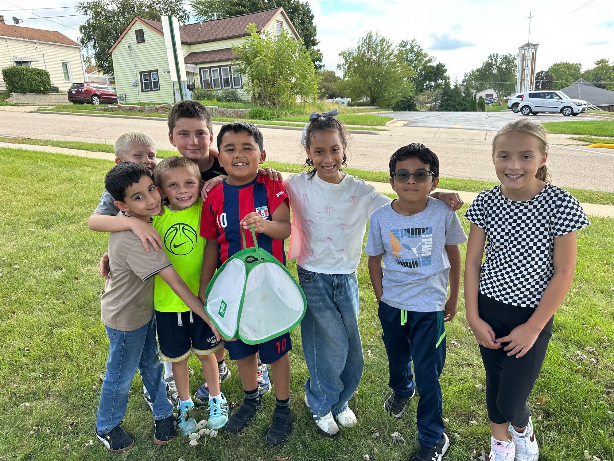 Students gather on the lawn around a mesh habitat as they release monarch butterflies
